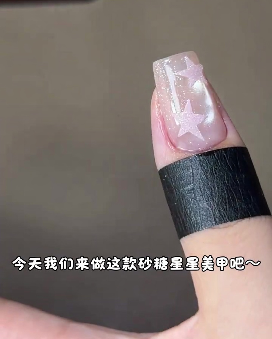 Ein Fingernagel mit einem rosa Sterndesign wird unter einer UV-Nagellampe ausgehärtet.