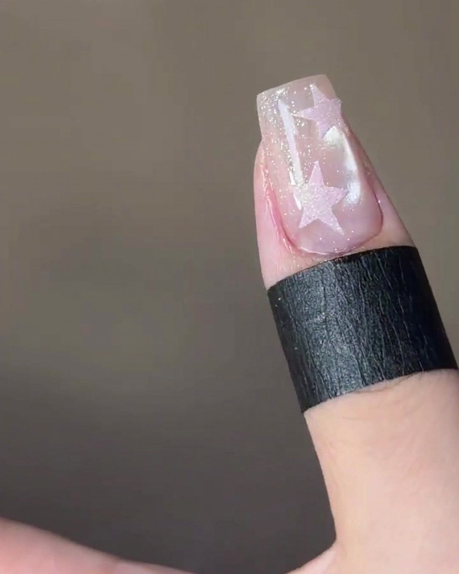 Ein sternförmiger Sticker wird auf die Spitze eines Fingernagels platziert.