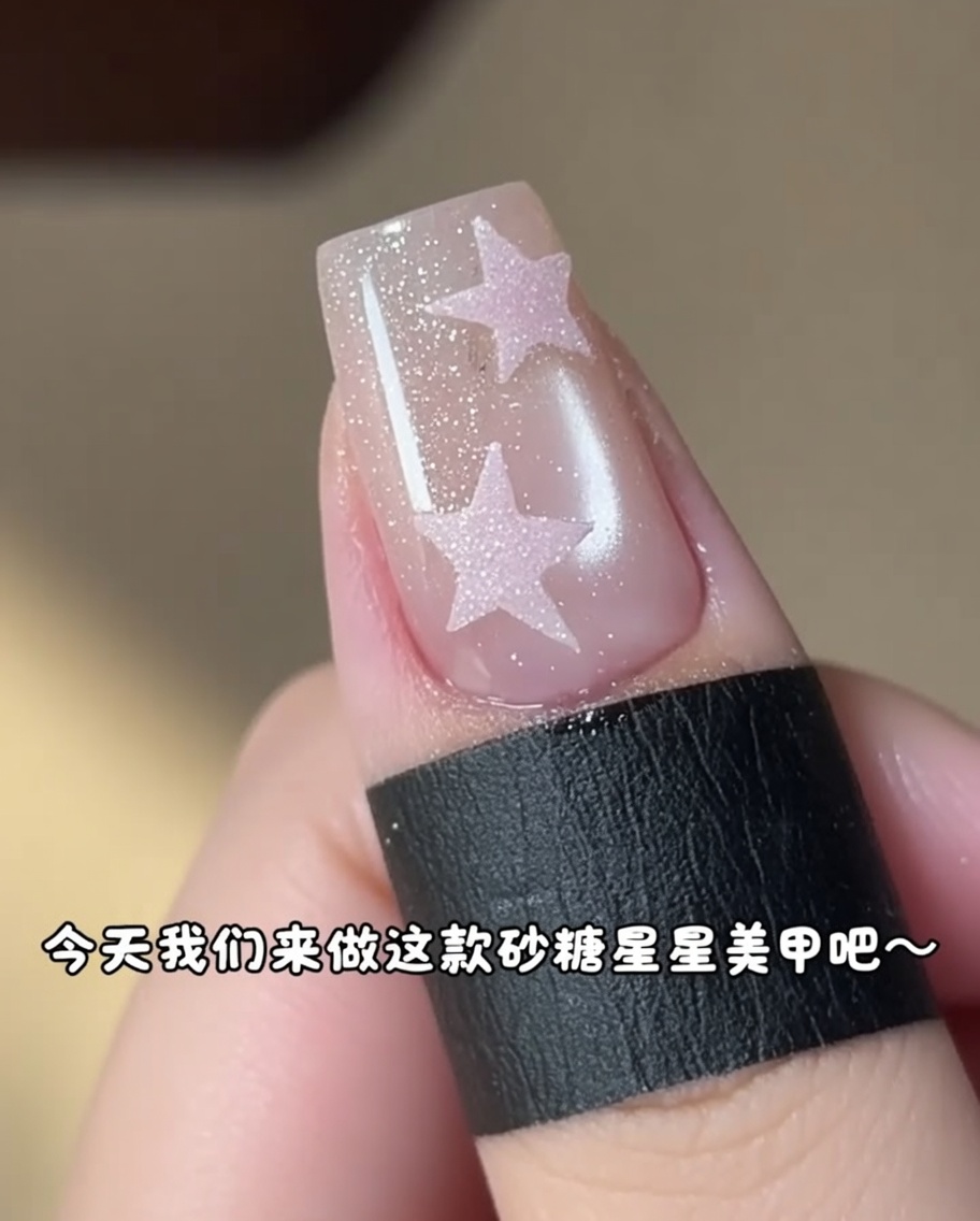 Ein kleiner Pinsel füllt rosa Gel in einen Stern-Sticker auf einem Nagel.