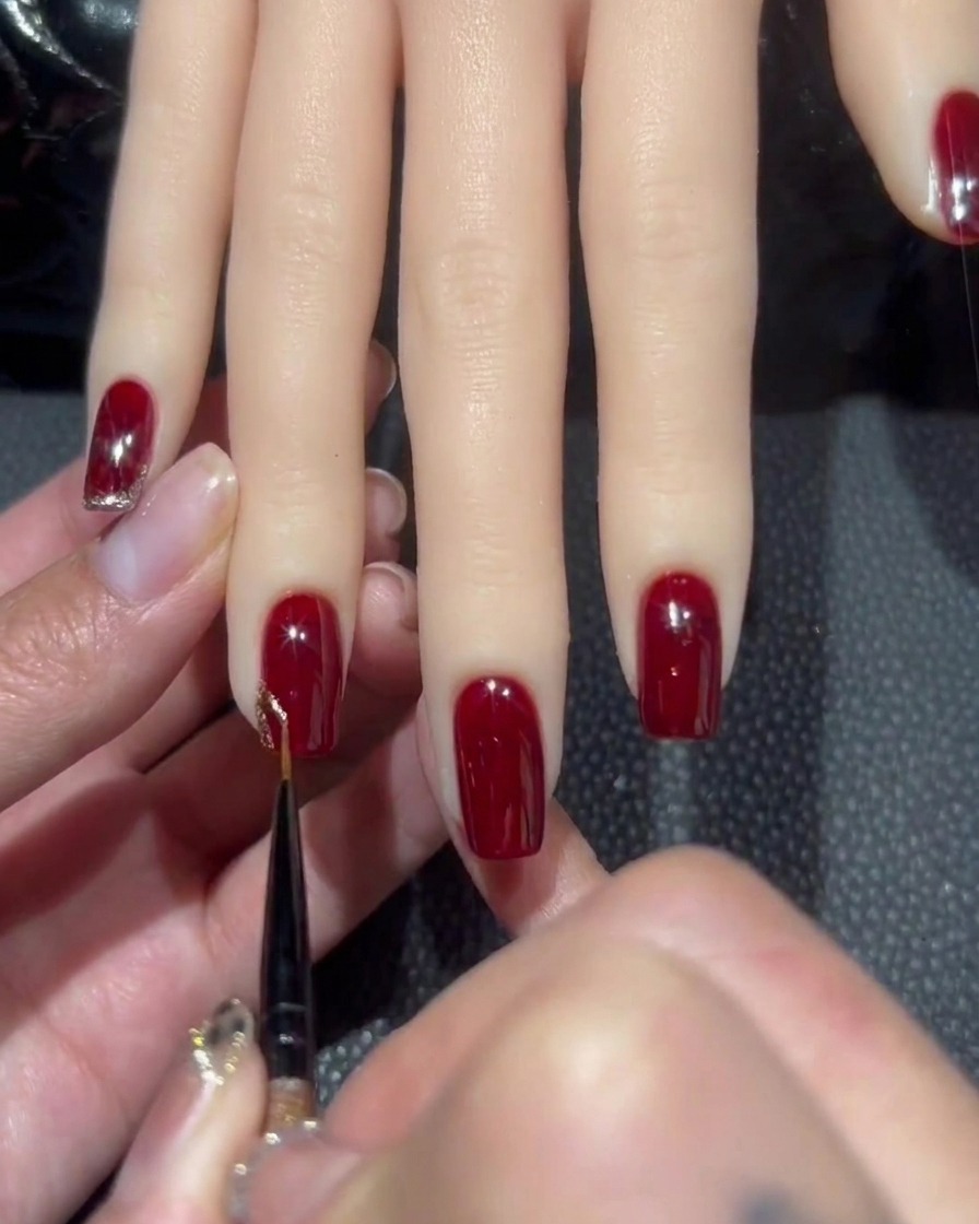 Ein feiner Liner-Pinsel nimmt einen Tropfen dichtes Roségold-Glitter-Gel auf.