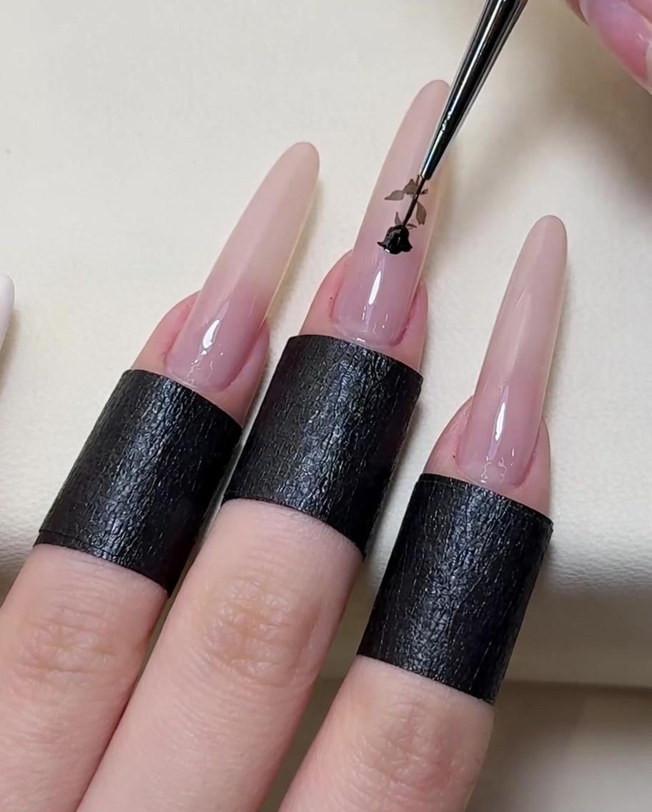 Ein feiner Detailpinsel zeichnet die Konturen der weißen Rose mit schwarzem Gel nach.