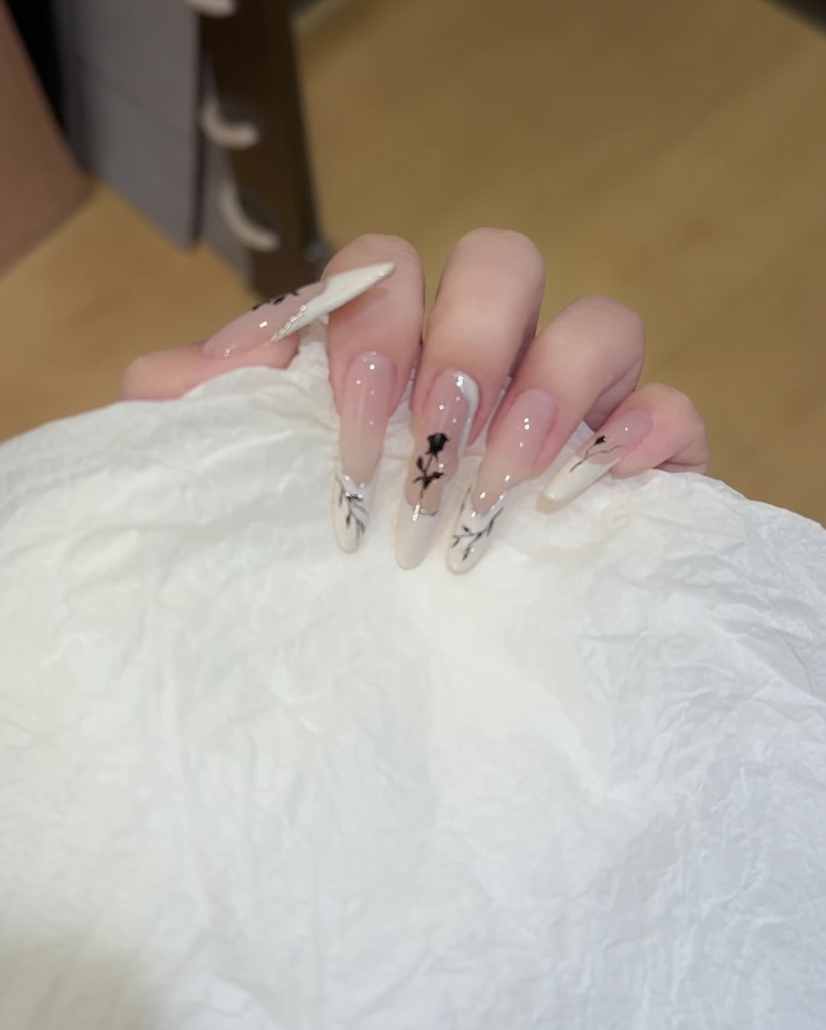 Nahaufnahme eines Pinsels, der weiße Farbe in einer Wellenform auf die Nagelspitze aufträgt.