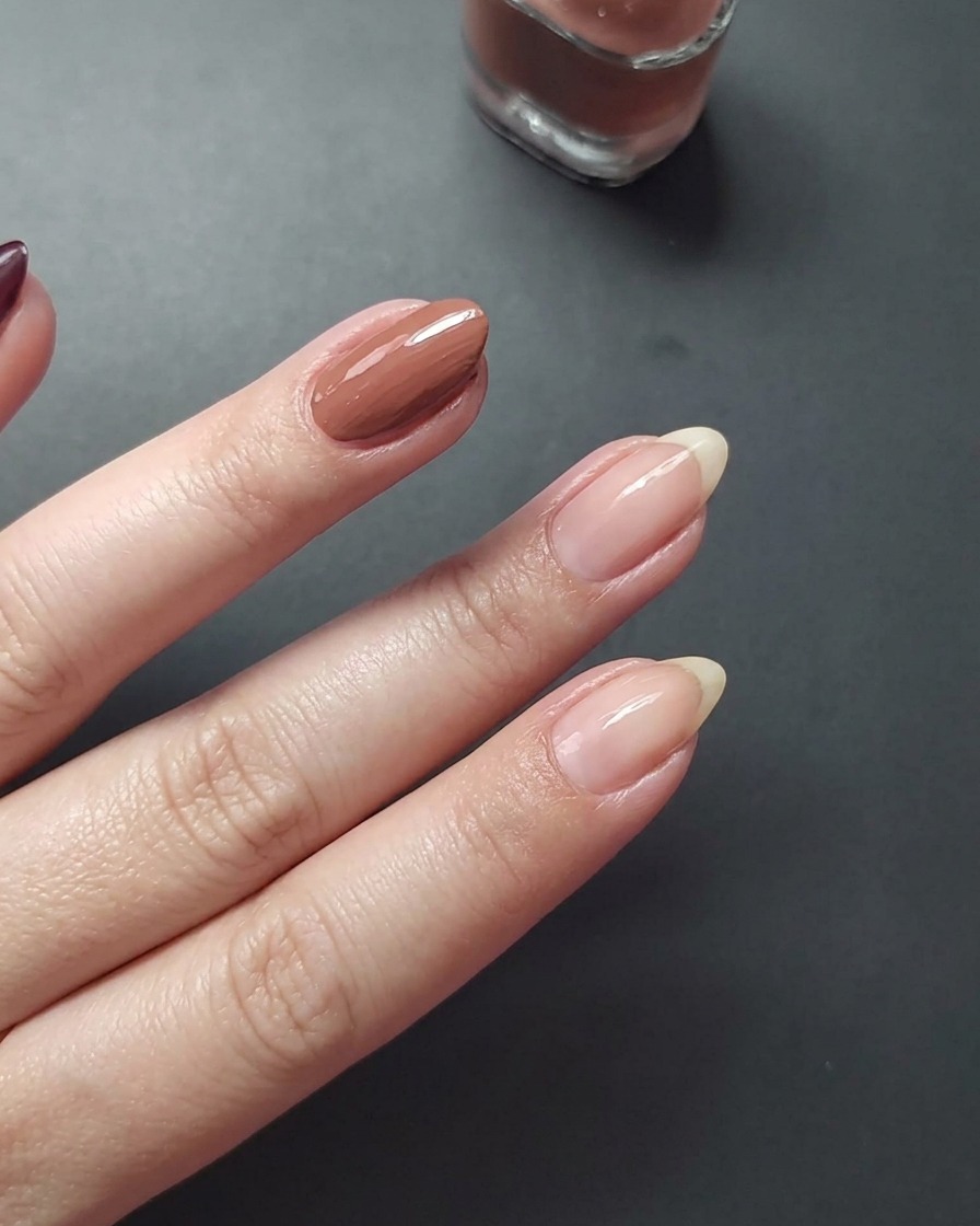 Nahaufnahme, die das Auftragen von mauvefarbenem Nagellack auf den Mittelfinger zeigt.