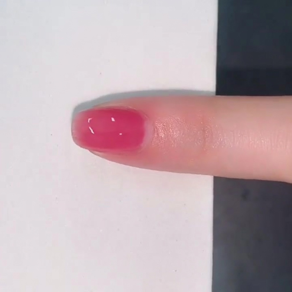 Ein einzelner Fingernagel, überzogen mit einer glänzenden, durchscheinenden Schicht pinkem Jelly-Lack.