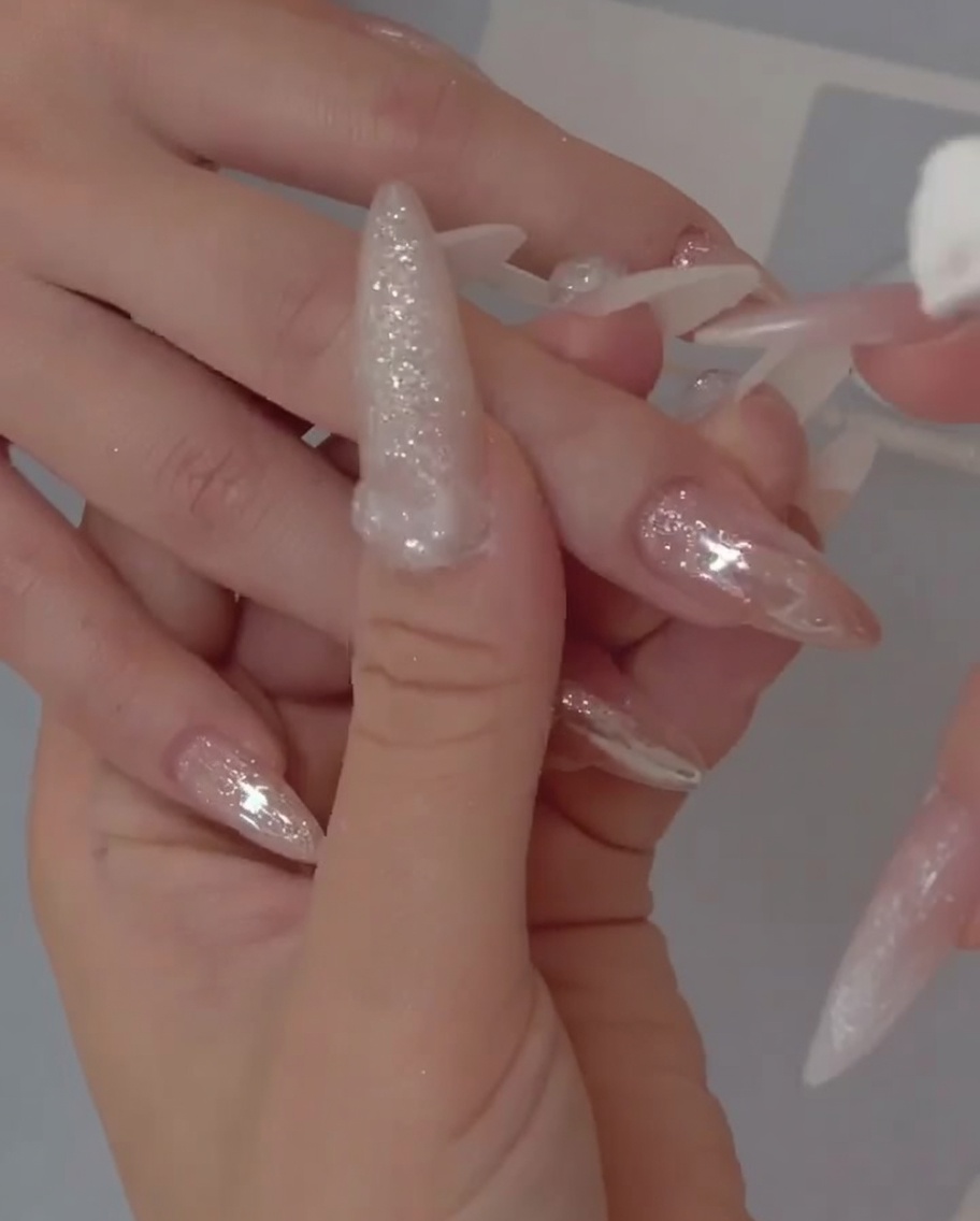 Nahaufnahme eines Pinsels, der eine transparente, geleeartige Gelschicht auf einen Naturnagel aufträgt.