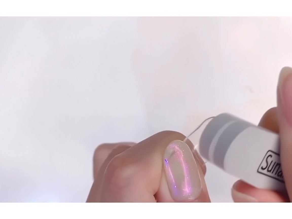 Eine feine Nagelfeile mattiert die Oberfläche eines transparenten Nageltips, bis kein Glanz mehr zu sehen ist.