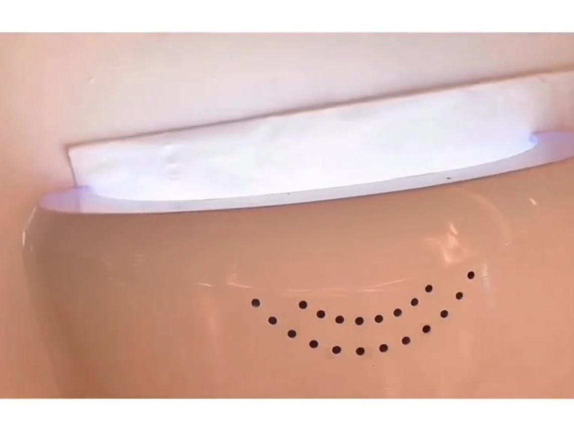 Eine Hand liegt unter einer leuchtenden LED-Nagellampe, um den aufgetragenen Base Coat auszuhärten.