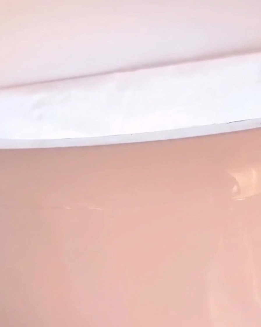 Nahaufnahme einer Hand in einer LED-Nagellampe, die ein pinkfarbenes Licht ausstrahlt.