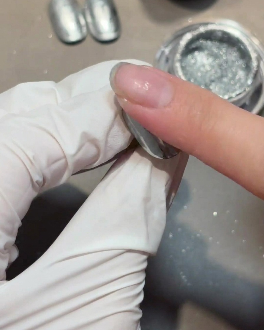 Auftragen einer klaren Schicht Aufbau-Gel über einen mit Chrom bedeckten Nagel.