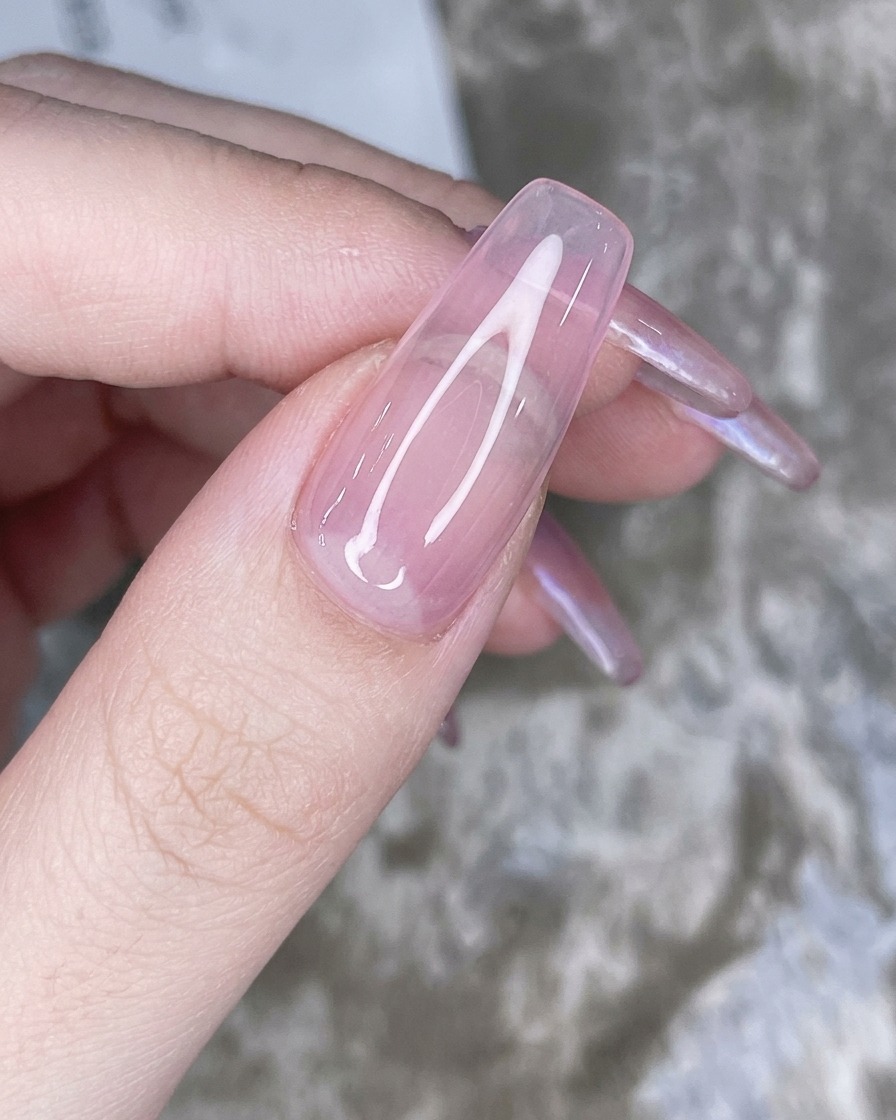Ein Schwamm-Applikator tupft irisierendes Chrompuder auf die Spitze des rosa Nagels.