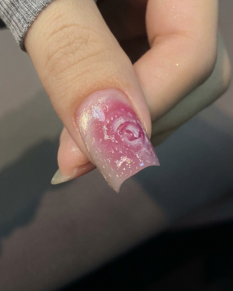 Nahaufnahme eines Pinsels, der einen klaren Base Coat auf einen natürlichen, unlackierten Fingernagel aufträgt.