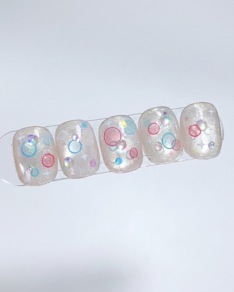 Ein Pinsel trägt eine Schicht Nude-Gel auf einen Nagel-Tip auf und tupft es für eine gleichmäßige Verteilung ein.