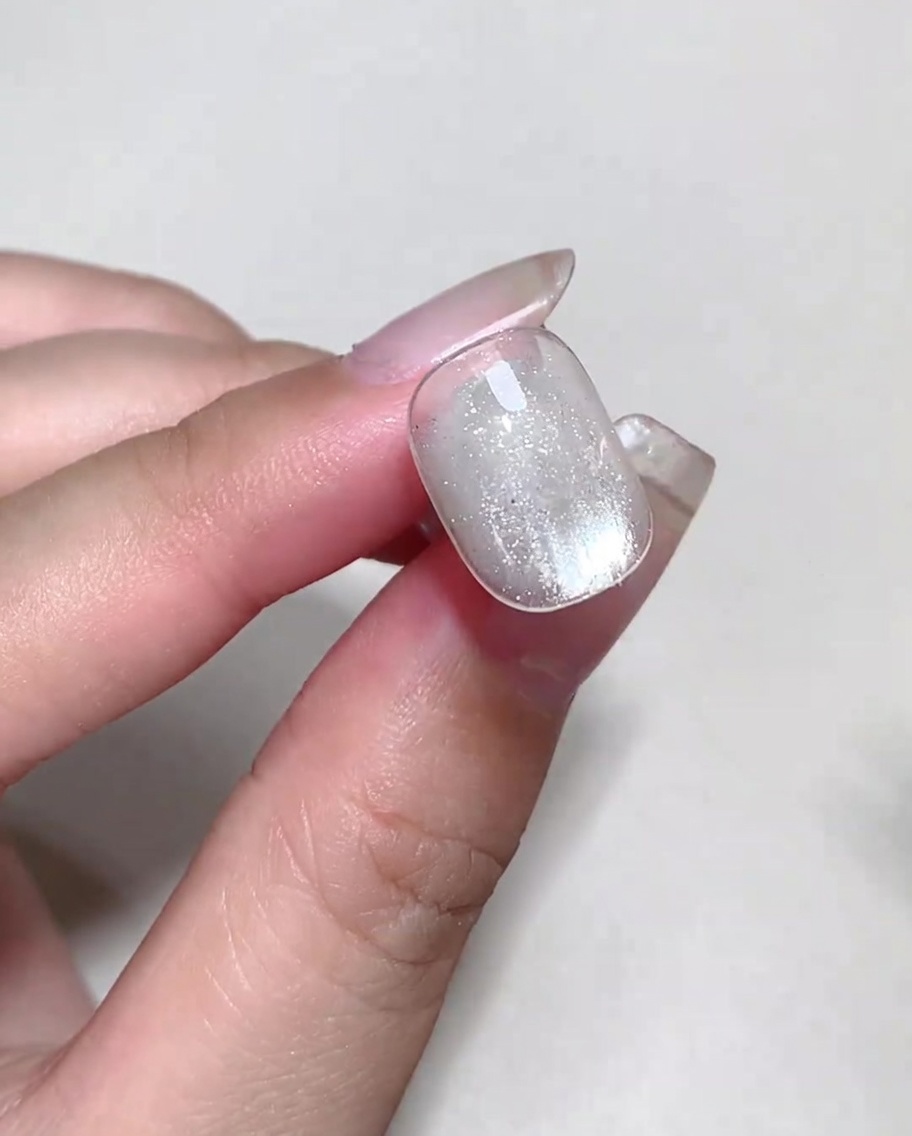 Bunte Blooming-Flüssigkeit wird mit einem Pinsel auf ein Nageldesign mit feuchtem Blooming-Gel aufgetupft, um Blasen zu bilden.