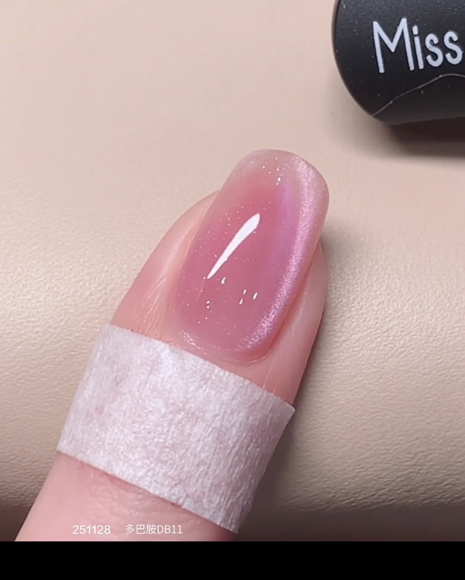 Ein Pinsel trägt eine frische, feuchte zweite Schicht pinken Cat-Eye-Lacks über die bereits ausgehärtete Schicht auf.