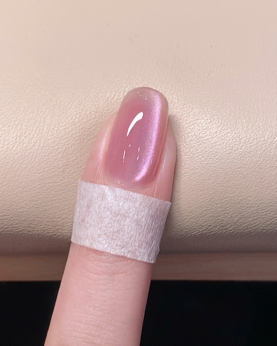 Eine Hand ruht in einer UV/LED-Lampe, während der letzte Überlack aushärtet.