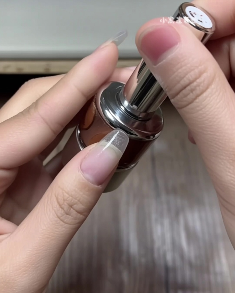 Hand, die mit einer Pinzette einen geschwungenen French-Tip-Aufkleber von einem Bogen abzieht.