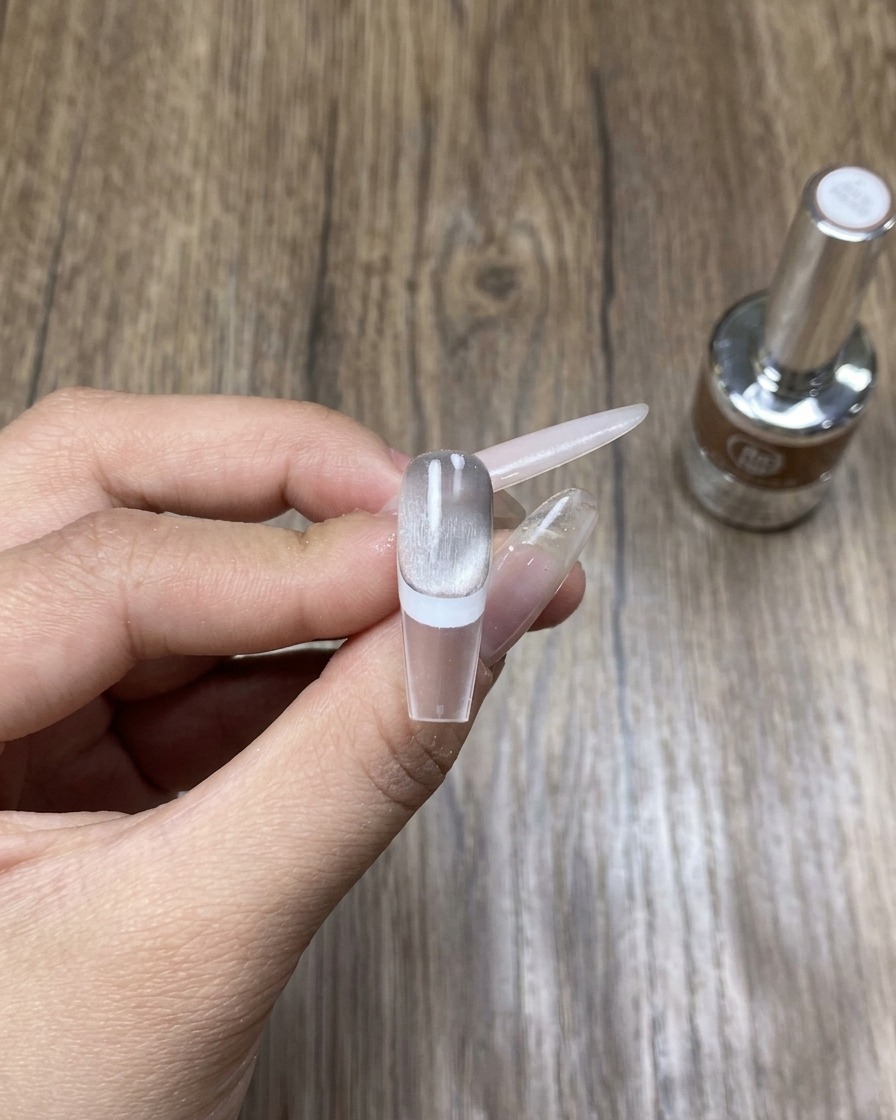 Hand in einer UV/LED-Lampe beim Aushärten des frischen Nageldesigns.