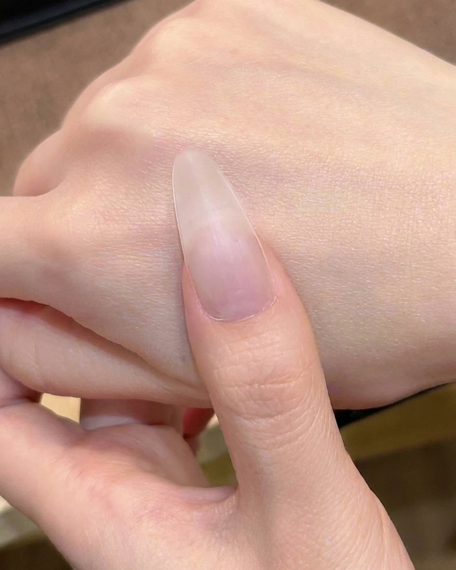 Die erste Schicht transparentes Nude-Pink-Gel wird mit einem Pinsel aufgetragen.
