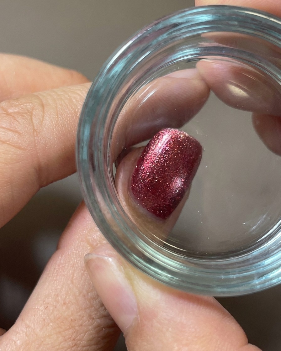 Nahaufnahme eines transparenten Silikonstempels, der ein weißes Food-Design auf einen roten Nagel mit Plüsch-Textur drückt.