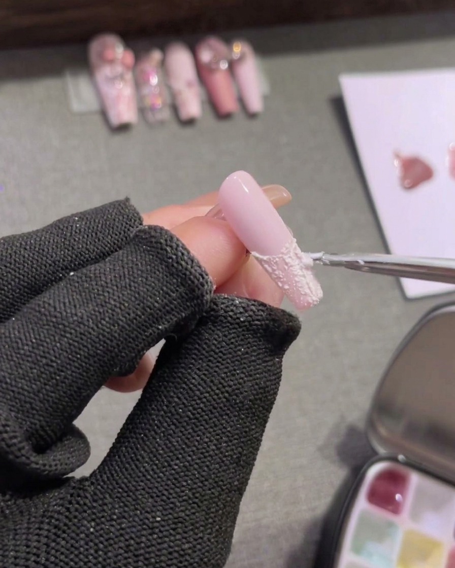 Ein Detailpinsel füllt die Nagelspitze mit deckendem, weißem Plaster-Gel aus.