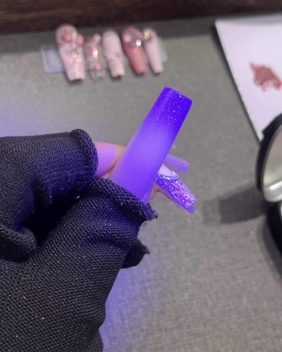 Eine Pinzette platziert eine kleine weiße Perle in das noch feuchte Plaster-Gel an der Smile-Line.