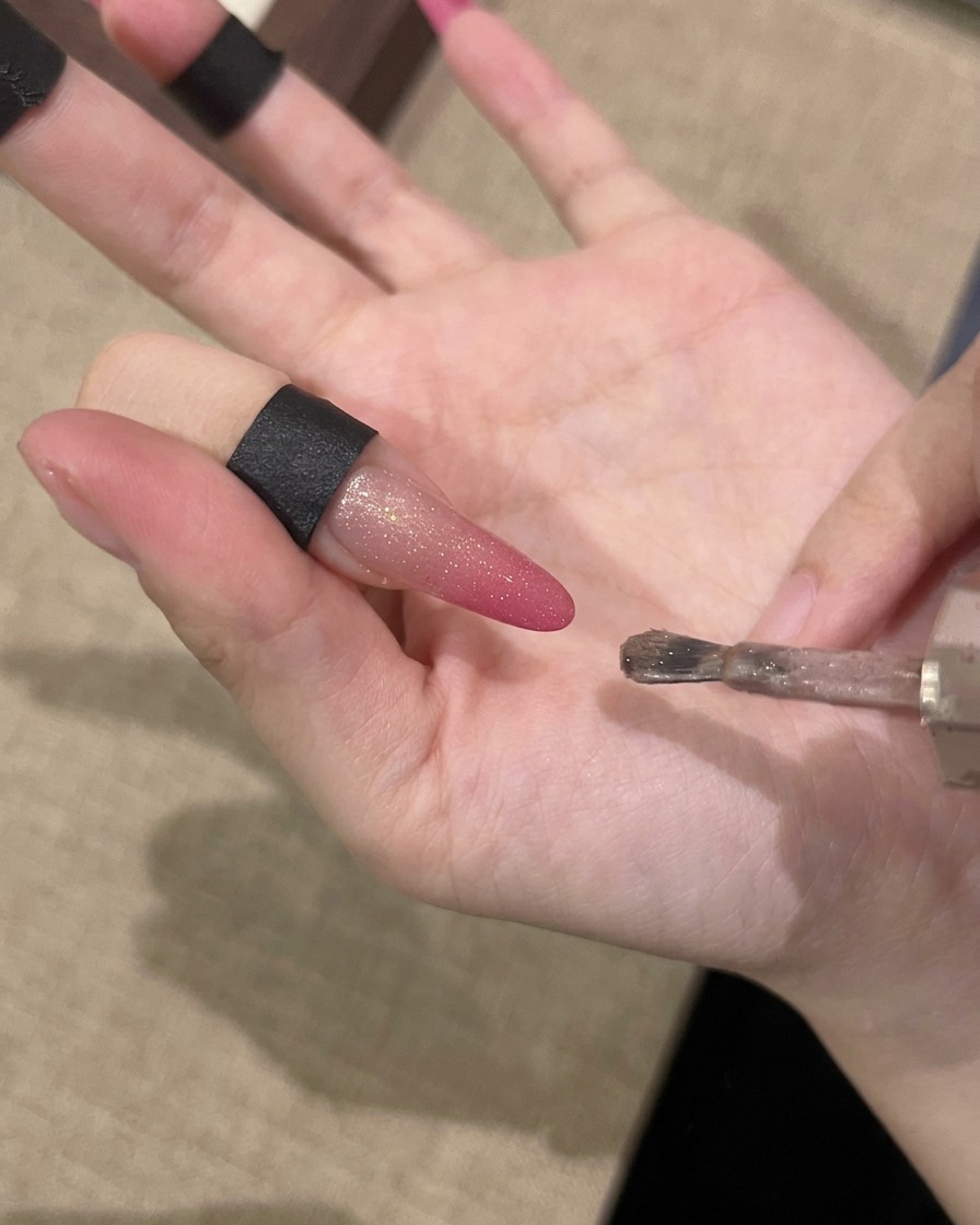 Eine Hand hält einen Magneten parallel zum Nagel, um den magnetischen Schimmer zu aktivieren.