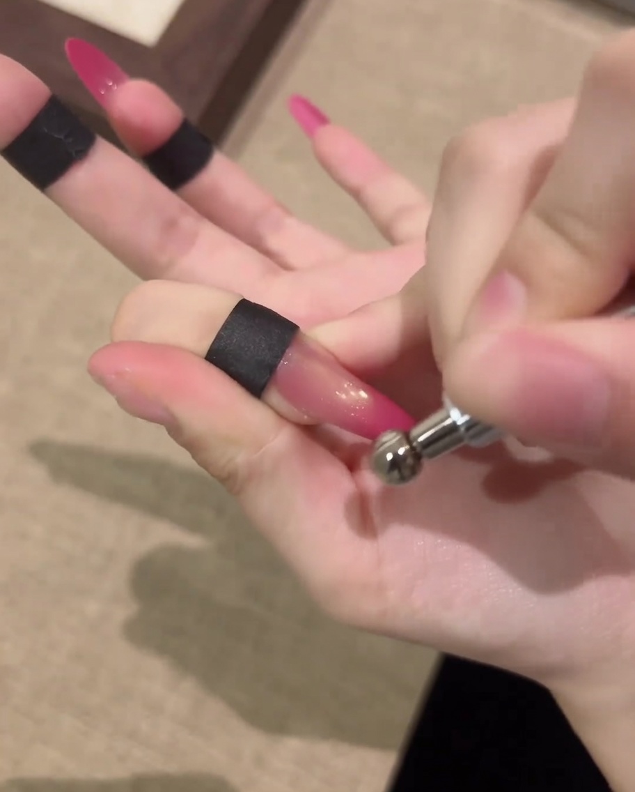 Eine Hand ruht in einer professionellen UV-Nagellampe, um das Cat-Eye-Gelnageldesign auszuhärten.