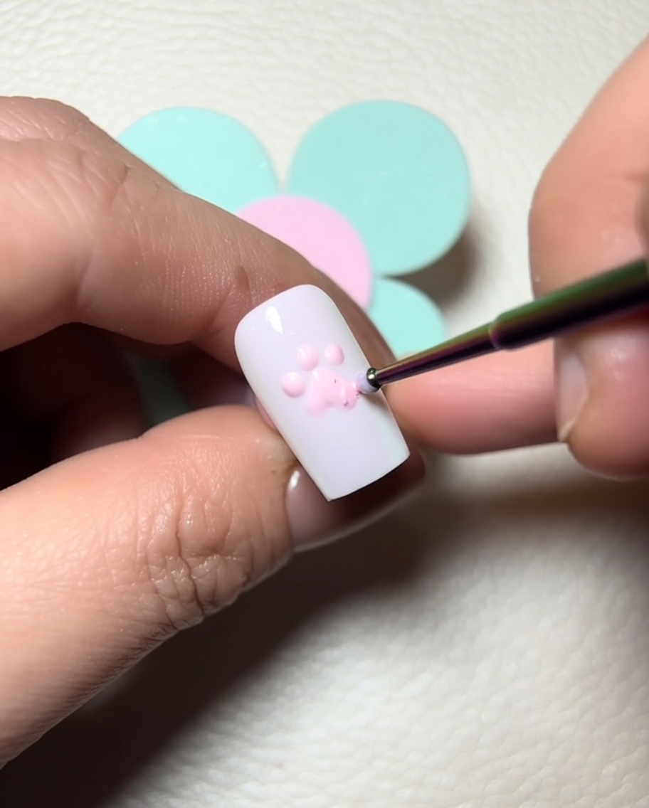 Ein Detailpinsel trägt klares Modelliergel auf die rosafarbenen Zehenballen auf, um Dimension zu erzeugen.