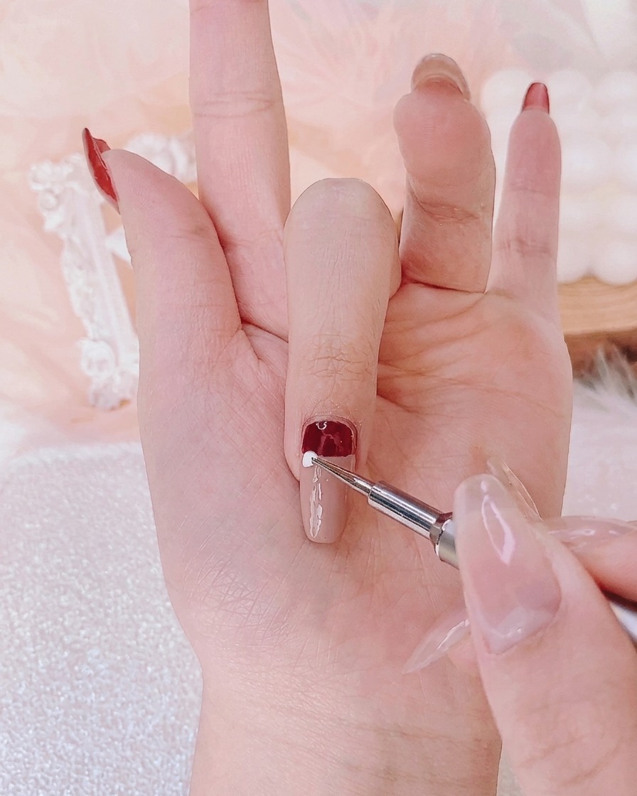 Ein Dotting-Tool setzt einen präzisen Punkt aus weißem Gel in die Mitte des Nagels.