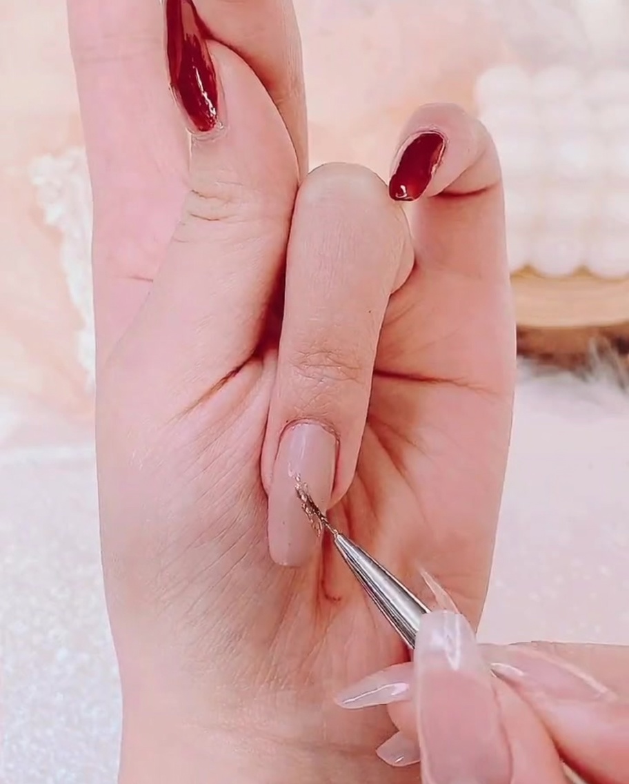 Ein Detailpinsel trägt eine dünne Schicht schimmerndes Goldgel in die Mitte des Nagels auf.