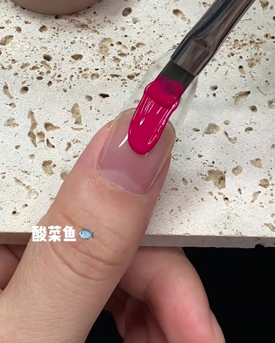 Ein Pinselstrich mit leuchtend pinkem Gellack, der in der Mitte der Nagelplatte nach unten gezogen wird.