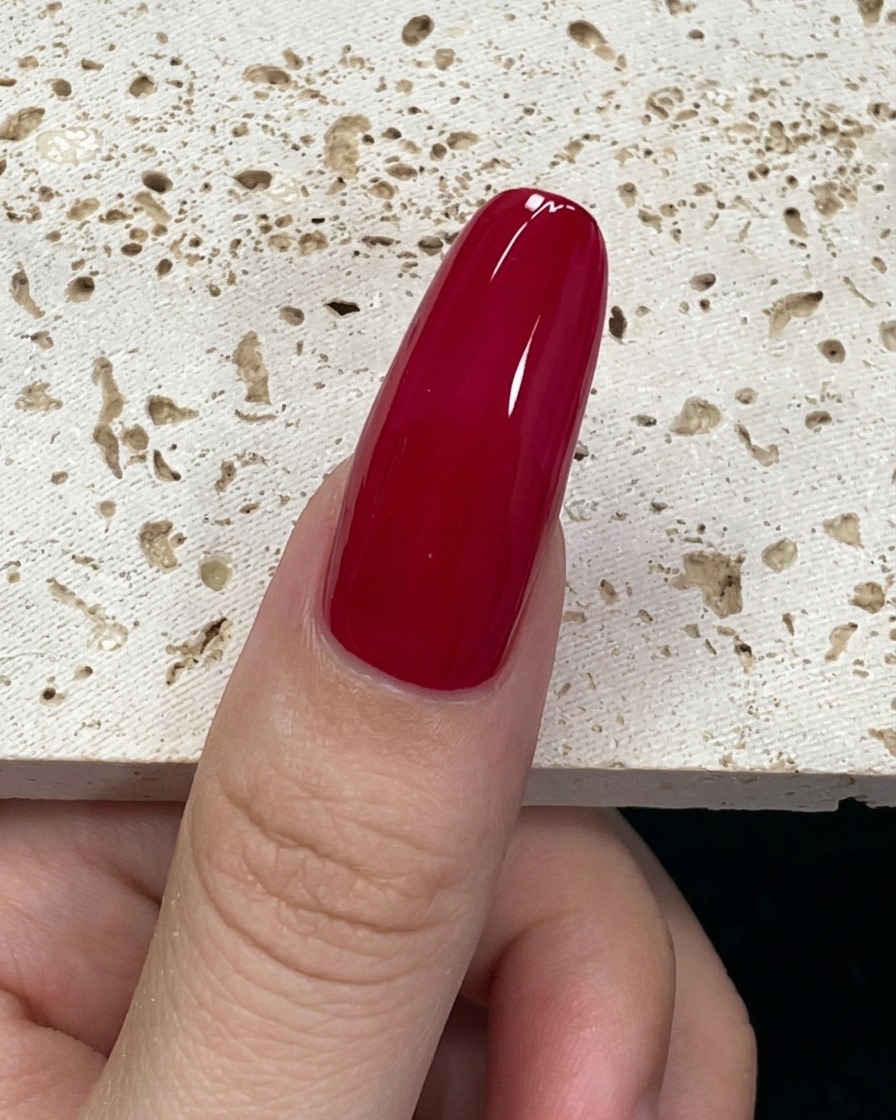 Ein mit mintgrünem Gellack beladener Pinsel am Ansatz des Nagels in einer Nahaufnahme.
