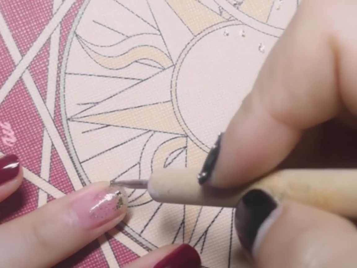 Ein Dotting-Tool platziert ein zartes Stück Goldfolie in der Mitte eines Nagels, der mit klebrigem Base Coat beschichtet ist.