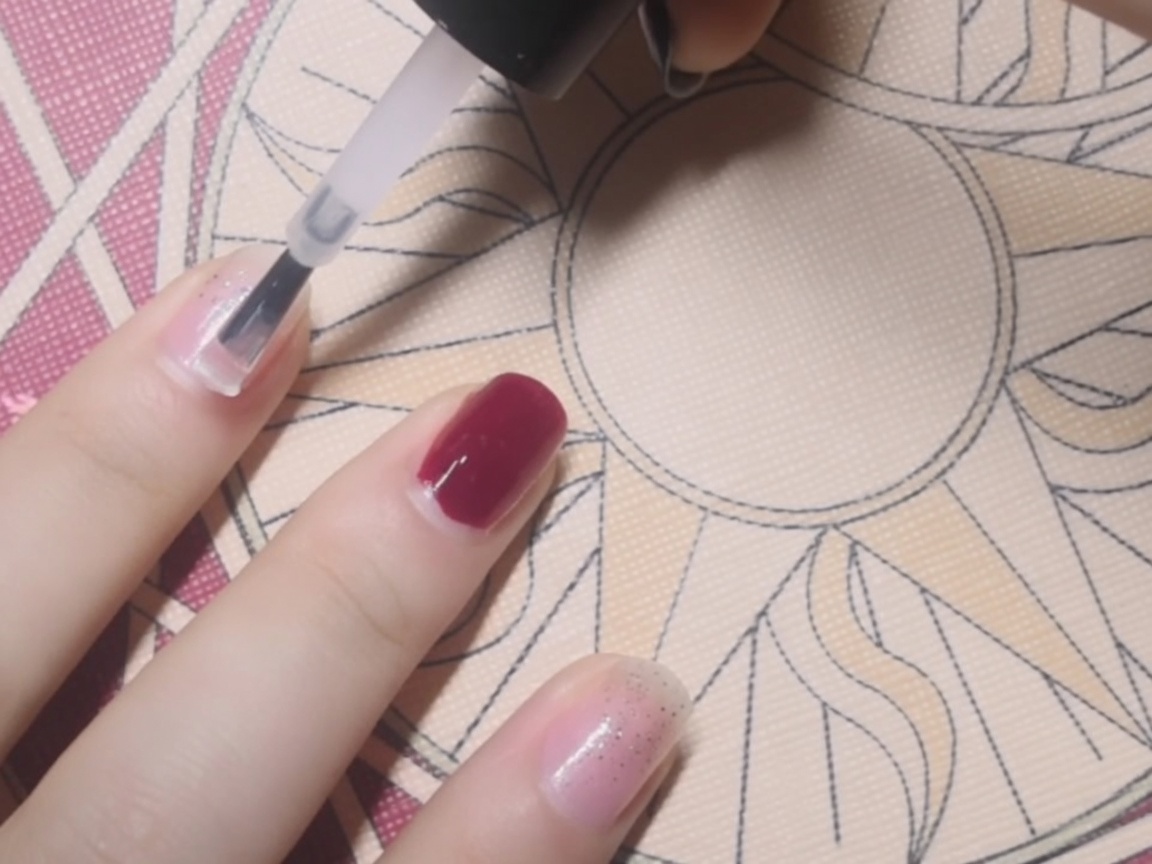 Nahaufnahme eines klaren Base Coats, der mit einem Pinsel auf einen Fingernagel aufgetragen wird.