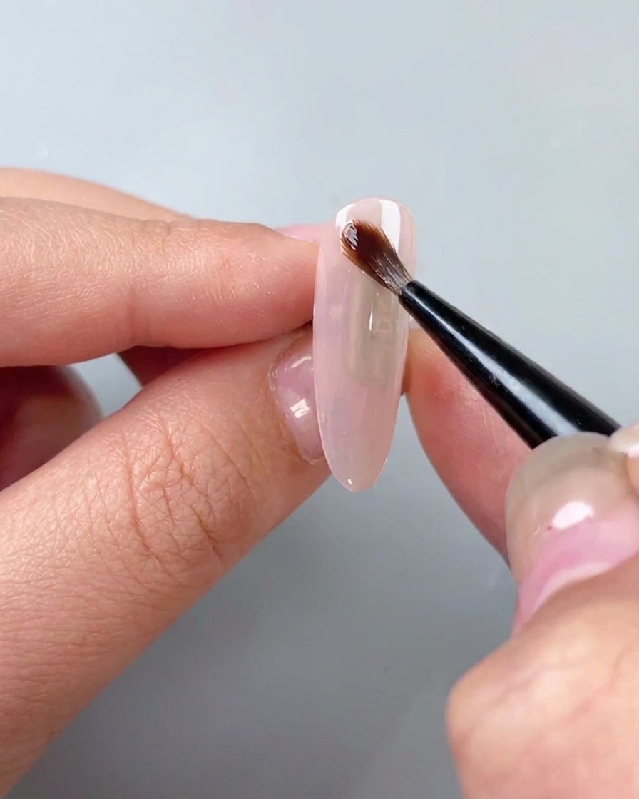 Ein Pinsel trägt klares Aquarell-Blooming-Gel über einen Basislack auf.