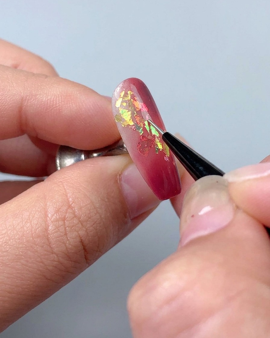Ein Liner-Pinsel wird verwendet, um feine dekorative Linien mit Strukturiergel auf einen manikürten Nagel zu zeichnen.