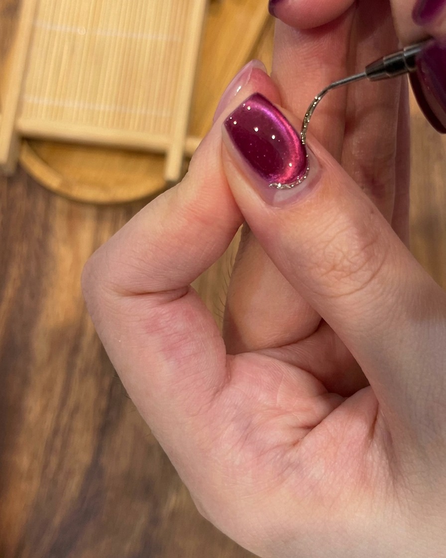 Ein Metall-Nagelhautschieber wird verwendet, um die Nagelhaut sanft zurückzuschieben.
