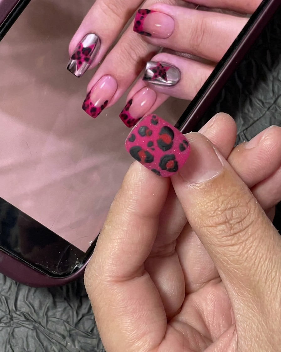 Ein kleiner Nageltip wird mit einem professionellen Pinsel mit leuchtend pinkem Gellack lackiert.