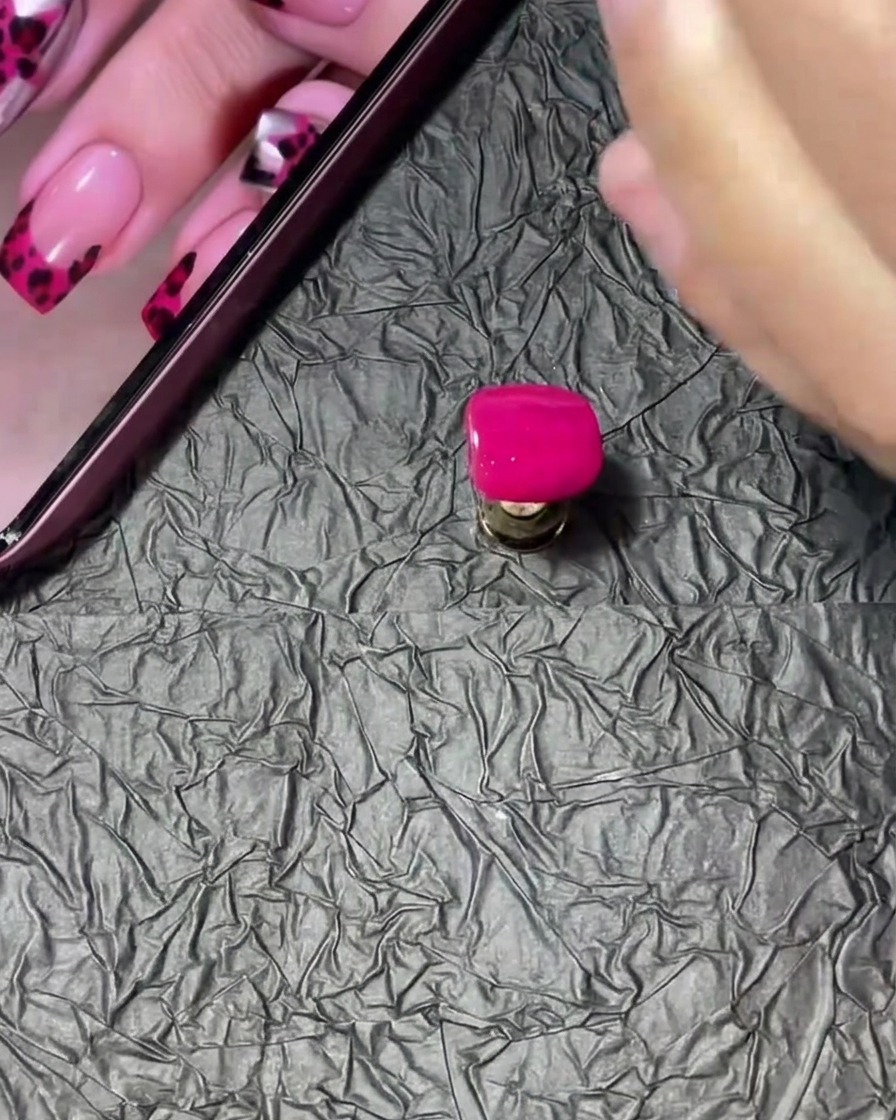 Ein Nageltip wird vorsichtig in einen kleinen Tiegel mit klarem Acrylpulver getaucht und gedreht.