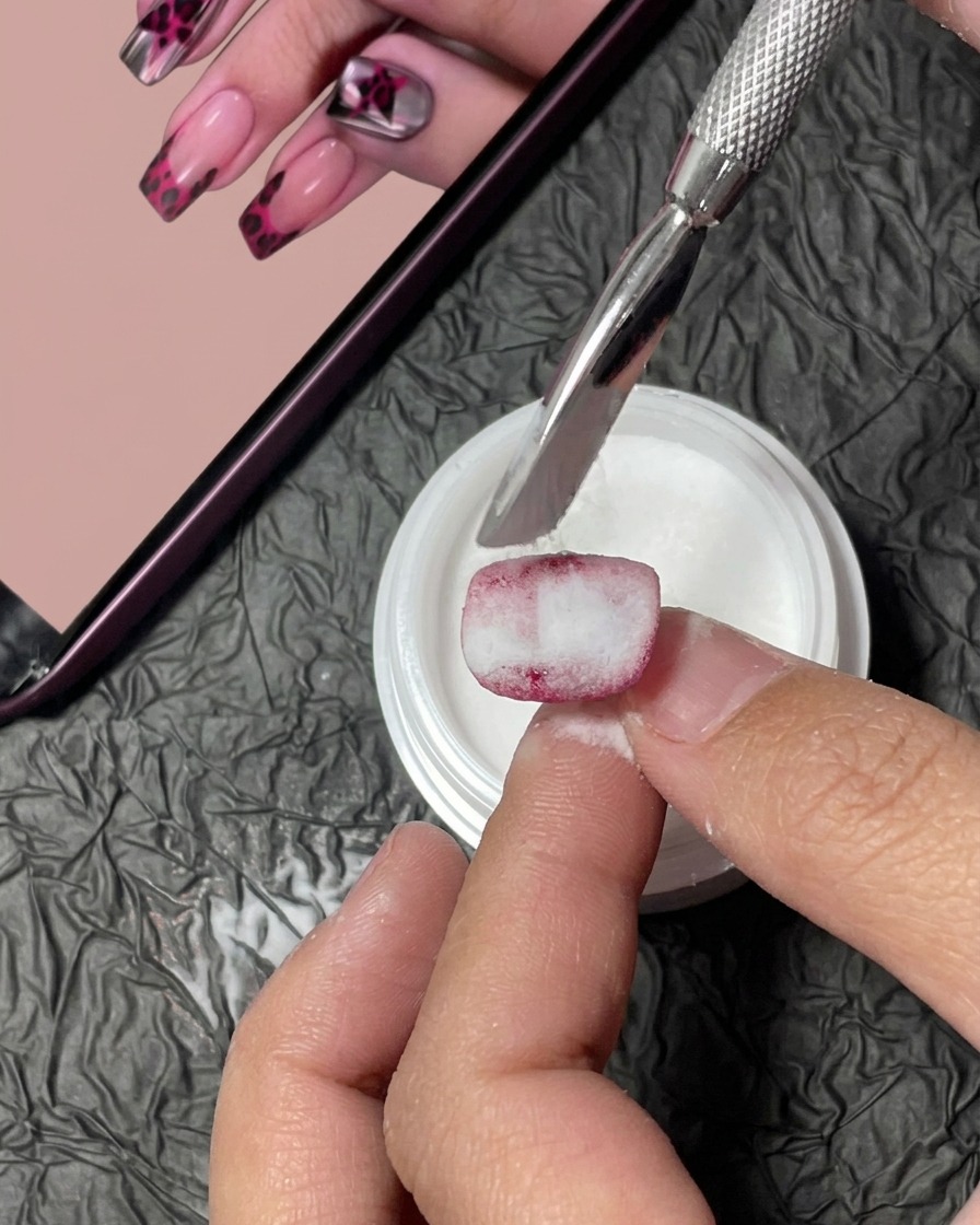 Nahaufnahme eines Nageltips unter dem warmen Licht einer UV-Lampe während des Aushärtungsprozesses.