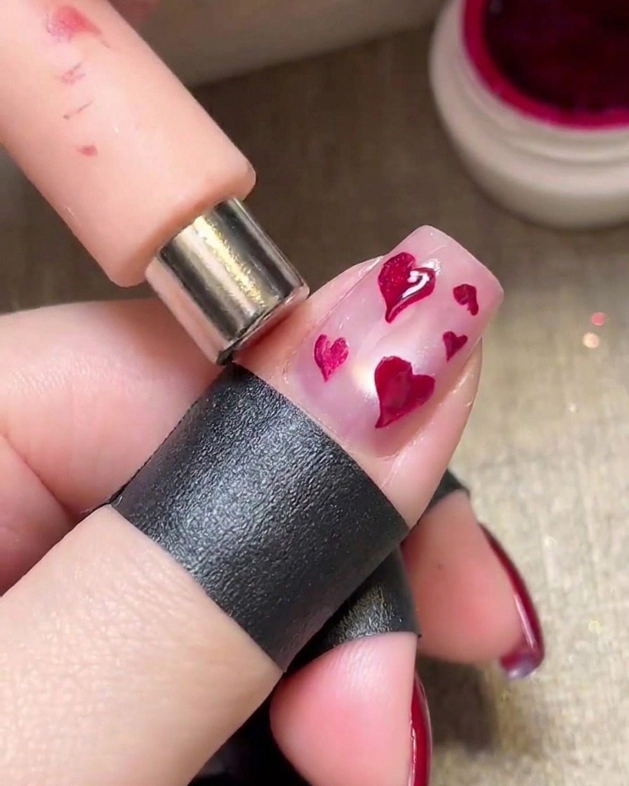Ein Magnet wird über feuchte Magenta-Herzen gehalten, um einen schimmernden metallischen Effekt zu erzeugen.