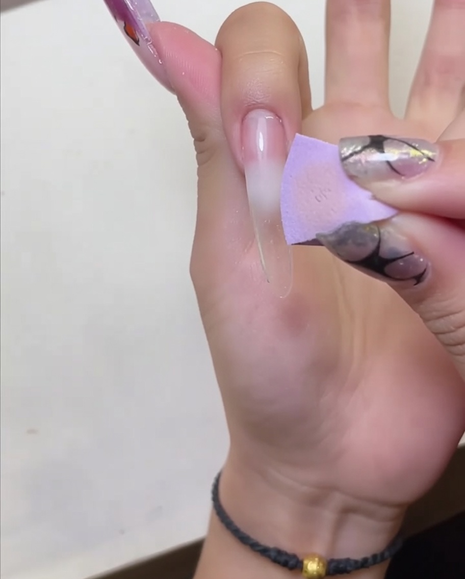 Eine Hand wird unter eine LED-Nagellampe gehalten, um den Peel-off Base Coat auszuhärten.