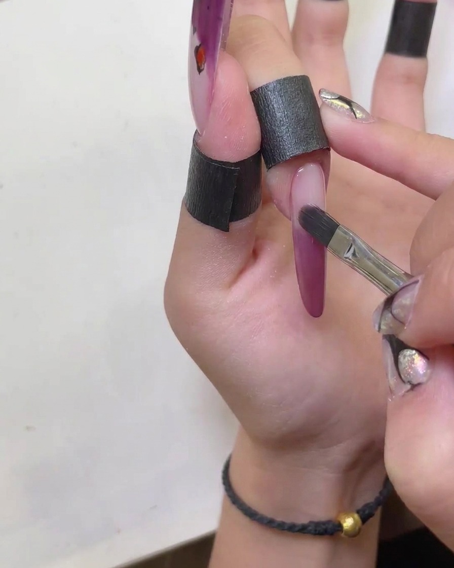 Ein Pinsel wird genutzt, um die Kanten der roten Cat-Eye French-Spitze sauber zu formen.