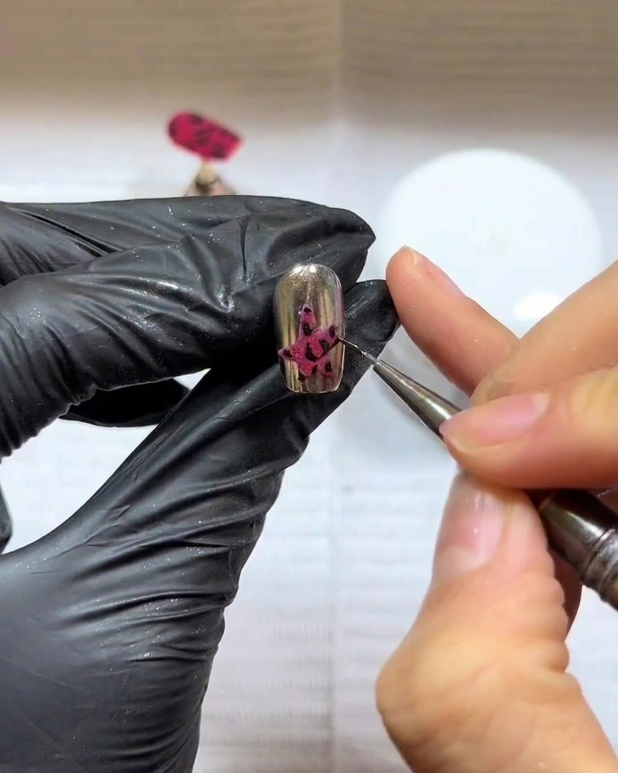 Eine Nahaufnahme eines manikürten Nagels mit einem dunklen Sternen-Design, positioniert unter einer professionellen UV/LED-Nagellampe zum Aushärten.
