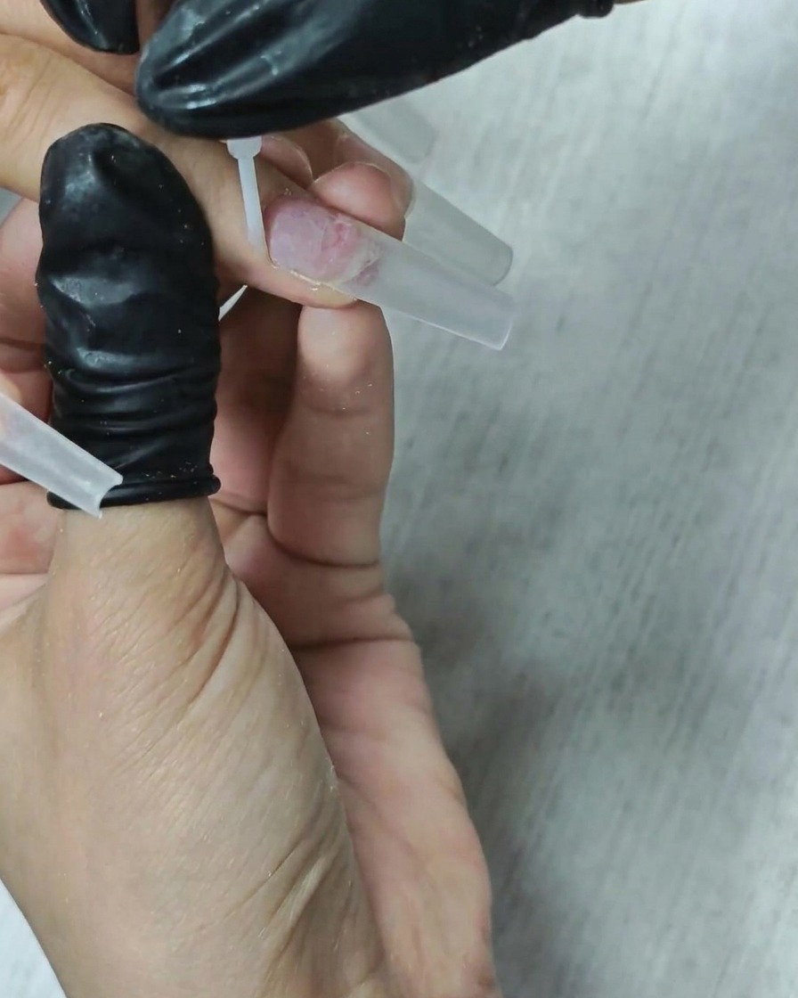 Ein Pinsel trägt einen klaren Dehydrator auf den Nagel auf.