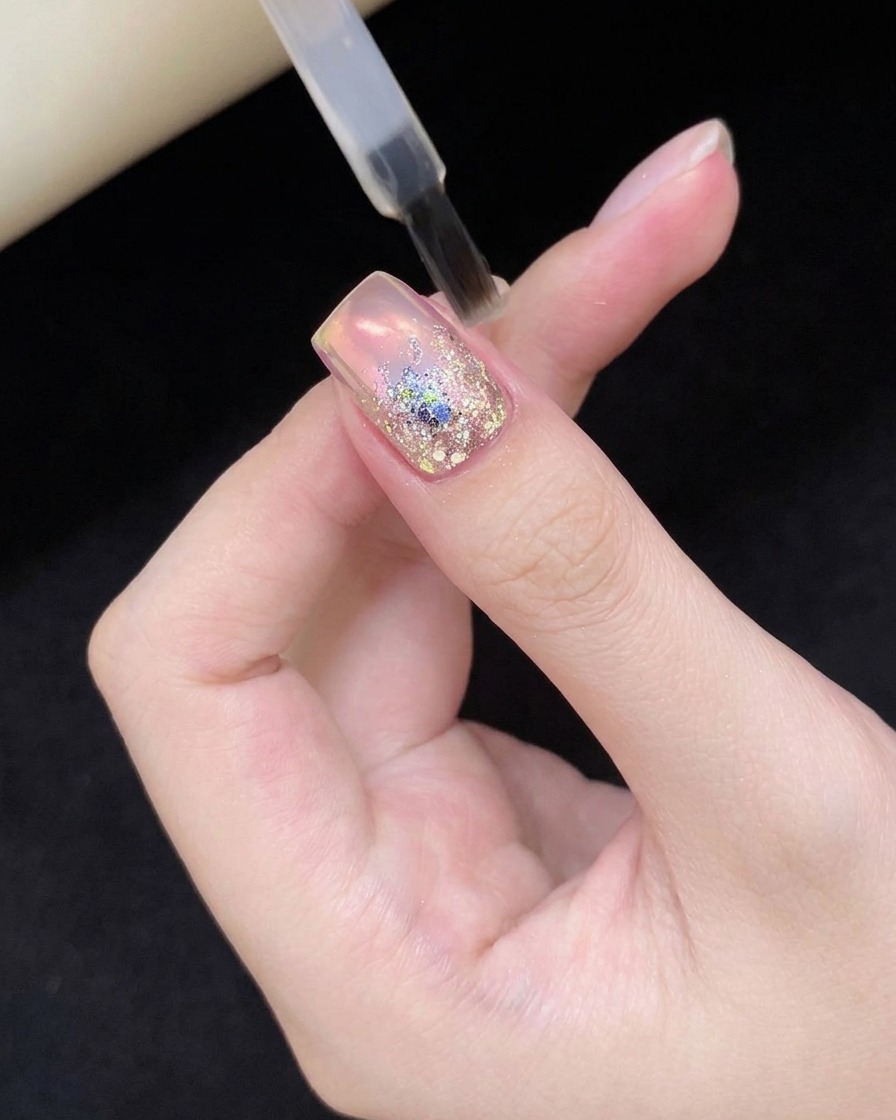 Ein Fingernagel mit Glitter-Nail-Art wird in eine UV/LED-Lampe gehalten.