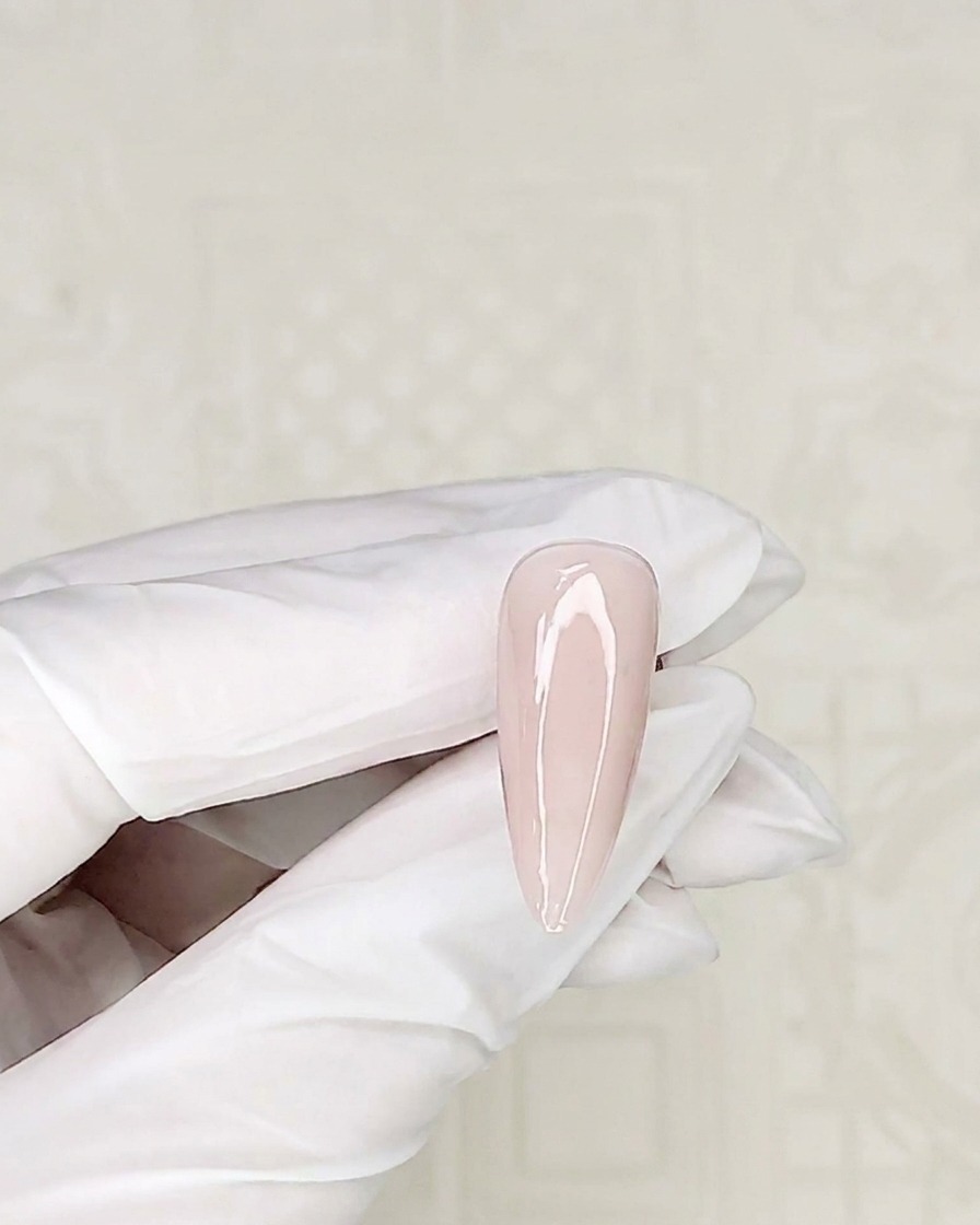 Ein Detailpinsel nimmt etwas weißes Gel aus einem Tiegel auf.