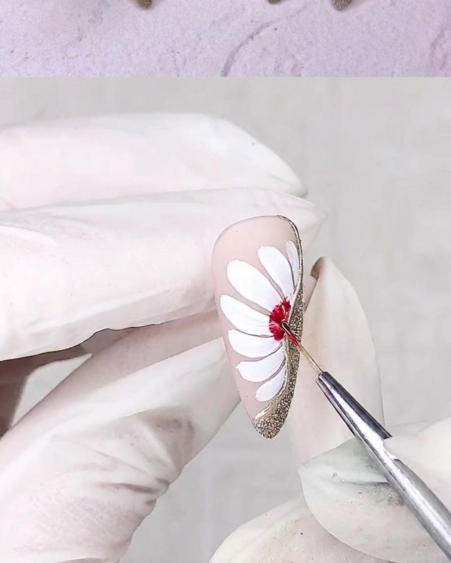 Ein Detailpinsel malt mit rotem Gel die Mitte einer Gänseblümchen-Blüte.