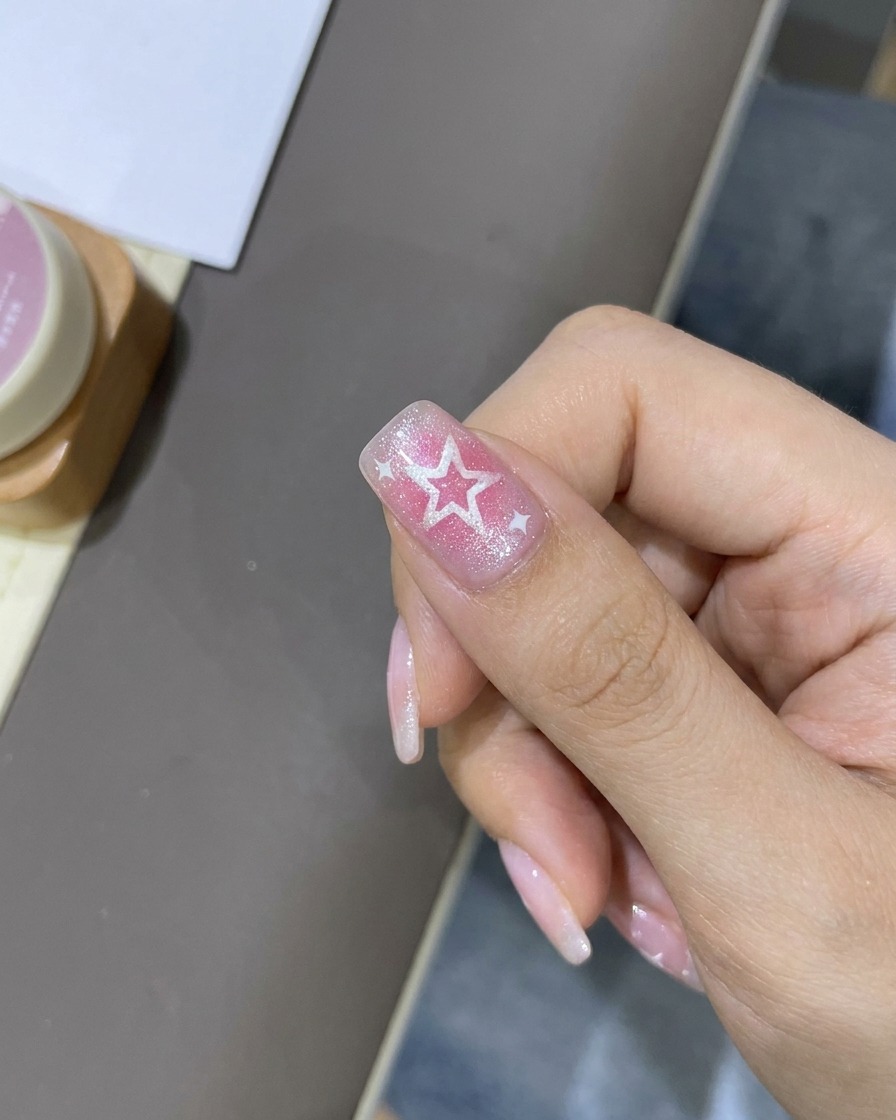Ein feiner Liner-Pinsel fügt dünne weiße Highlights um die Sterndesigns auf dem Nagel hinzu.