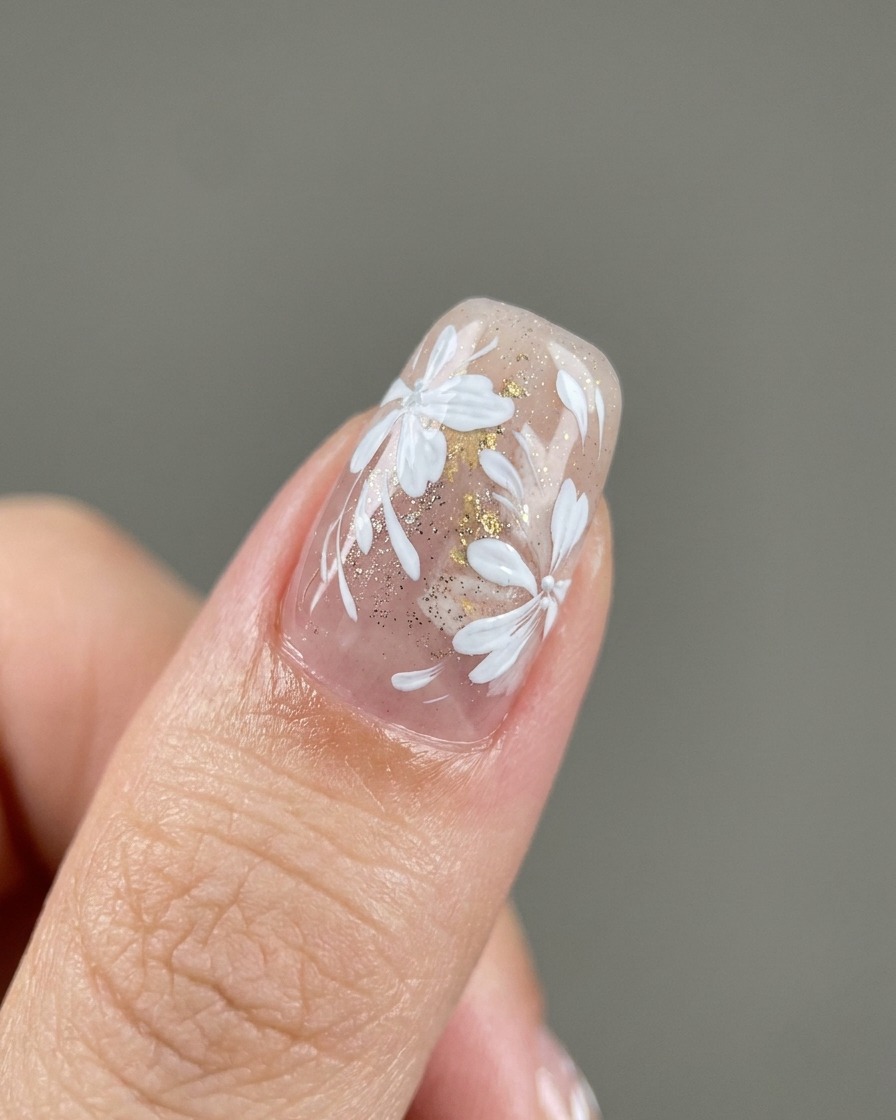 Ein Detail-Pinsel platziert kleine Blattgold-Stückchen auf einem Nagel.